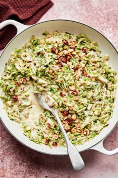 a bowl filled with coleslaw and nuts on top of a pink tablecloth