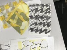 several pieces of art are displayed on a table with black and white papers, yellow and gray designs