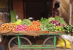 a man standing next to a cart filled with lots of fruits and veggies