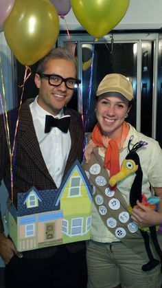 a man and woman are posing for a photo with balloons in the shape of houses