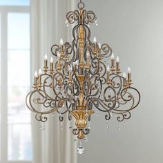 an ornate chandelier hangs from the ceiling in front of a white curtained window