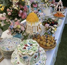 a table topped with lots of plates covered in flowers and cake on top of it