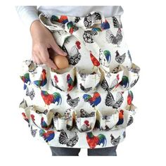 a woman is holding an egg in her hand while wearing a skirt with roosters on it