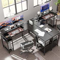 an office desk with two computers on it and a chair in front of the desk