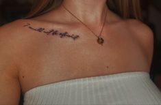 a woman wearing a white top has a tattoo on her chest that reads, happy birthday