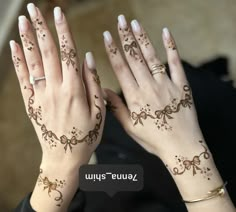 two hands with hendi designs on them and one hand holding the other's wrist