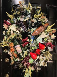 a wreath is hanging on the door with wine bottles and grapes in it, along with other holiday decorations