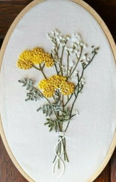 a close up of a embroidery on a wooden surface with yellow and white flowers in it