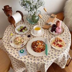 a table topped with plates of food next to a vase filled with flowers