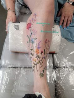 a woman's leg with flowers on it and her foot covered in plastic wrap