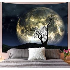 a bed with a large wall hanging in front of it that has a tree and moon on it