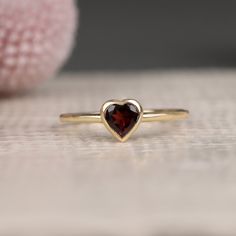 Ashly Follow your heart and it will lead you to our gold rings. This red heart ring has a beautiful heart shape cut and would make the perfect gift for her. Available in Yellow Gold, White Gold, and Rose Gold. - Handmade - Solid Gold- Natural Garnet- Total Garnet Carat Weight: .48 ctw- Bezel Setting Size: 7.5 mm- Ring Band: 1.4 mm All pieces come beautifully boxed in suede pouches you can always use (which really comes in handy when traveling!) Gold Rings Heart, Dainty Garnet Ring, Garnet Heart Ring, Vintage Promise Rings, Red Heart Ring, Promise Ring Gold, Gold Garnet Ring, Golden Rings, Garnet Heart