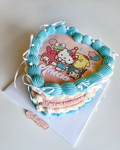 a hello kitty birthday cake on top of a white table with blue ribbon around it