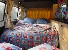 a bed in the back of a camper with two pillows and blankets on it