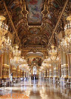 an ornate hall with chandeliers and paintings on the ceiling, in a palace