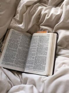 an open book sitting on top of a bed