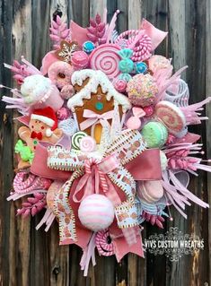 a wreath made out of candy, candies and other items is hanging on a wooden fence