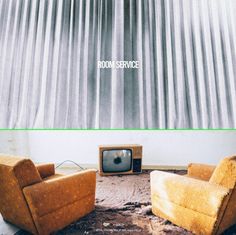 two chairs and a television in front of a curtained wall with the words room service on it