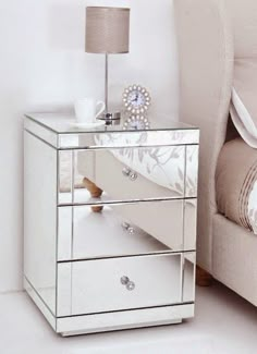 a mirrored bedside table with two drawers and a lamp on it next to a couch