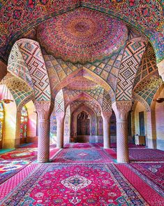 the inside of an ornate building with many colorful carpets and arches, all covered in intricate designs