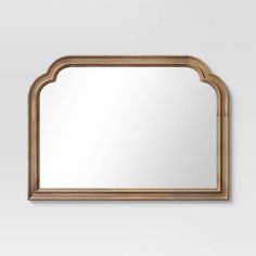 an arched mirror on the wall with a light wood frame and gold trimmings