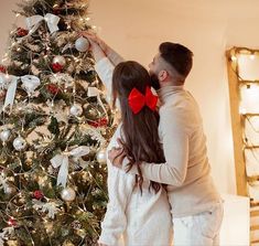 a man and woman standing in front of a christmas tree