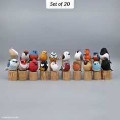 a group of stuffed birds sitting on top of wooden posts in front of a gray background