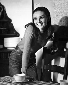 black and white photograph of a woman leaning over a table with a coffee cup on it