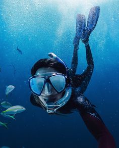 a person wearing a diving mask and snorkels in the water with fish around them