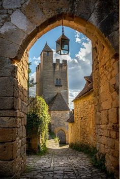 an archway leading to a stone building with a light hanging from it's side