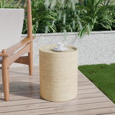 a cup of coffee sitting on top of a wooden table next to a chair and potted plant