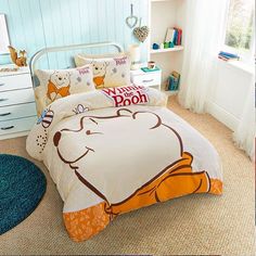 a bed with winnie the pooh comforter and pillow cases on top of it