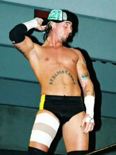 a man with no shirt on standing in a wrestling ring