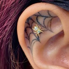 a close up of a person's ear with a spider tattoo on it