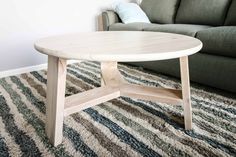 a coffee table sitting on top of a rug in front of a couch with pillows