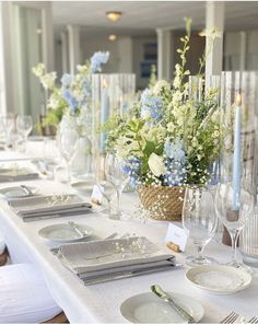 a long table with white and blue flowers in vases on it's sides