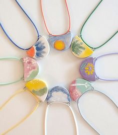 a group of different colored necklaces on a white table with flowers and clouds painted on them