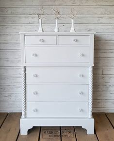 a white dresser with three vases on top