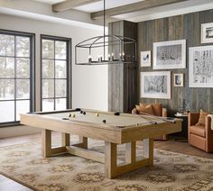 a living room with a pool table and couches in front of two large windows