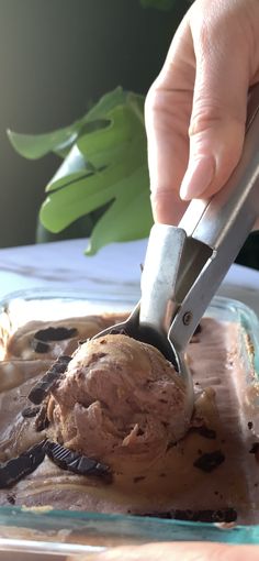 a person scooping ice cream out of a container with a pair of tongs