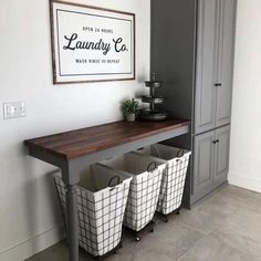 three laundry baskets sitting on top of a wooden table in front of a gray cabinet