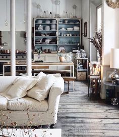 a living room filled with furniture and lots of shelves on the wall next to a window