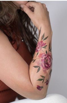 a woman with flowers on her arm is sitting down