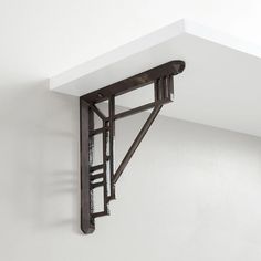 a metal shelf with a ladder hanging from it's side on a white wall