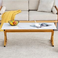 a coffee table with a bowl of fruit on it in front of a white couch