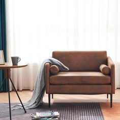 a living room with a couch, table and chair next to a large curtained window