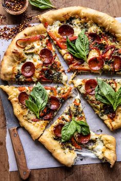 a pizza cut into eight slices on top of a cutting board with basil and pepperoni