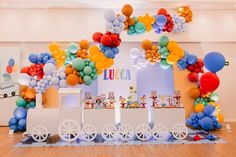 a train themed birthday party with balloons and streamers on the wall, along with an ice cream cart