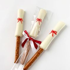 three pretzels wrapped in cellophane and tied with red ribbon on white surface