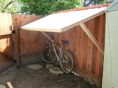 a bike is parked in front of a wooden fence with a awning over it